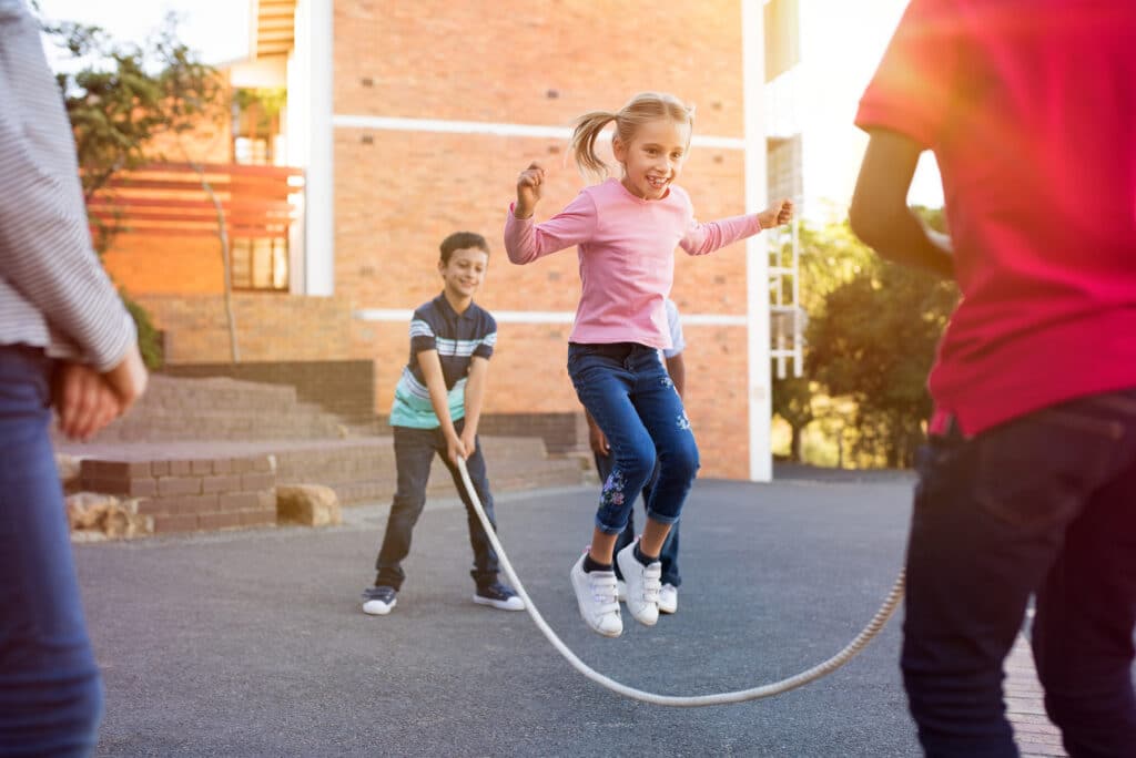 School children playing together with skipping rope
